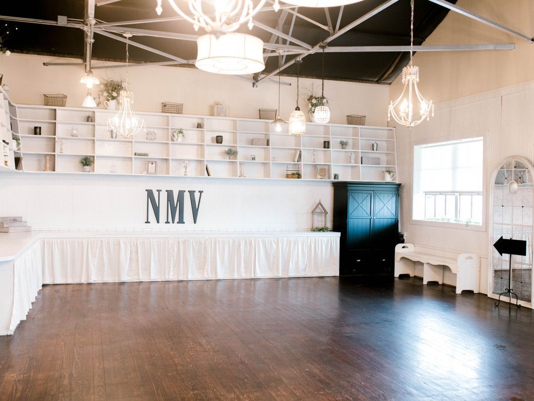 A large empty room with a wooden floor and a nmv sign on the wall.