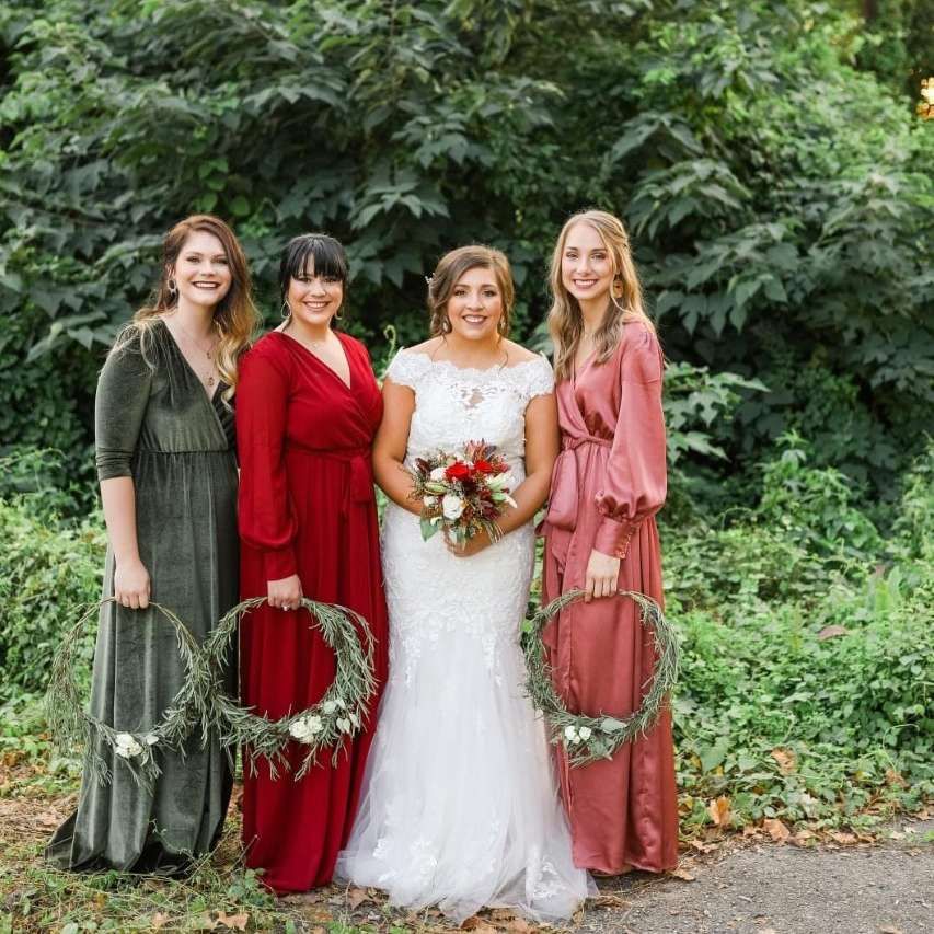 A bride and her bridesmaids are posing for a picture while holding wreaths.