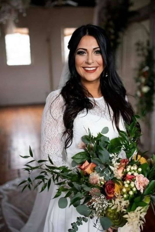 A bride in a white dress and veil is holding a bouquet of flowers.