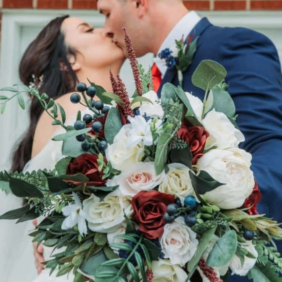 A bride and groom kissing while holding a bouquet of flowers