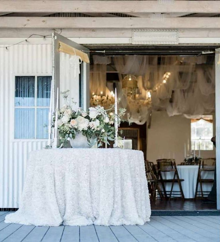 A table with flowers and candles on it in front of a building.