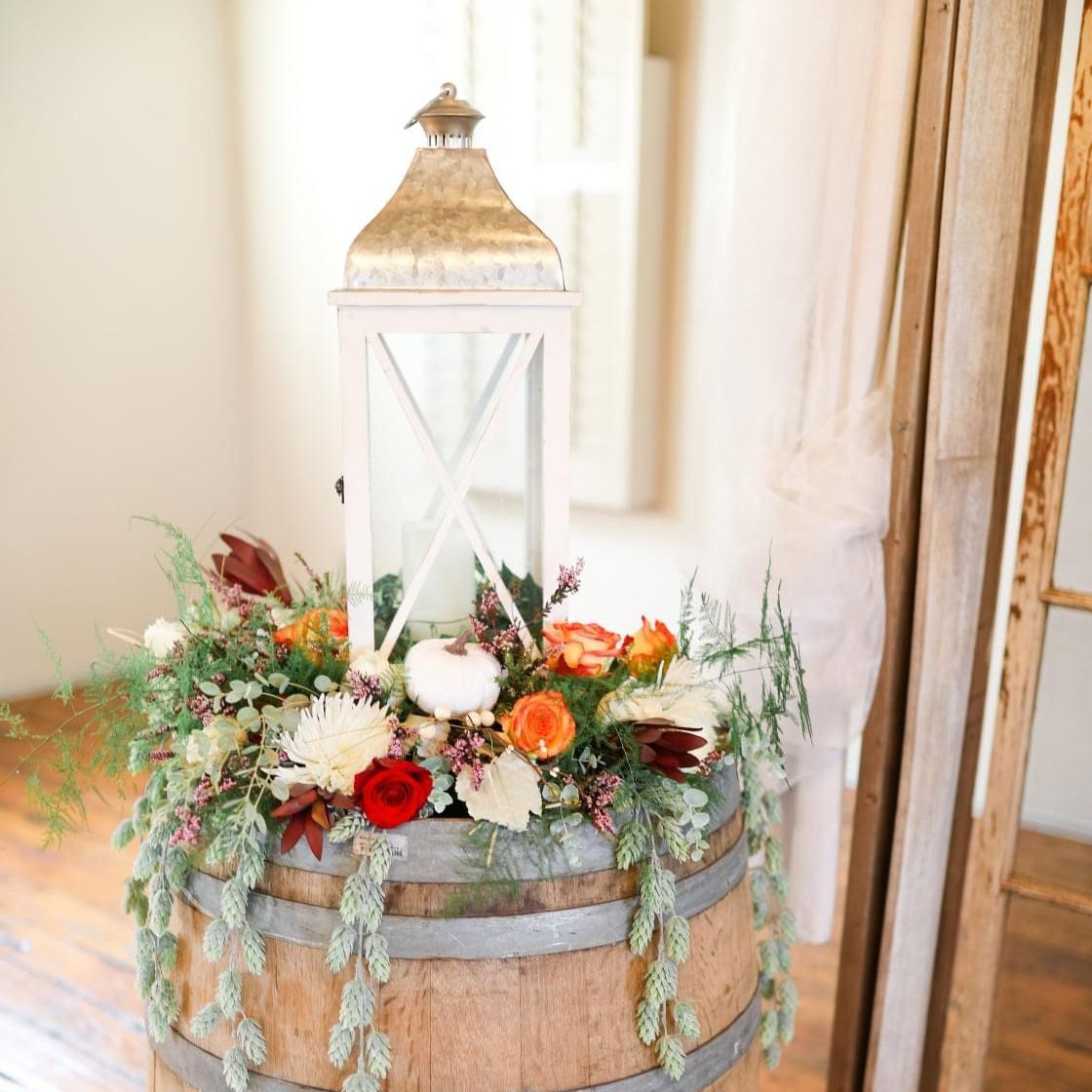 A wooden barrel filled with flowers and a lantern.