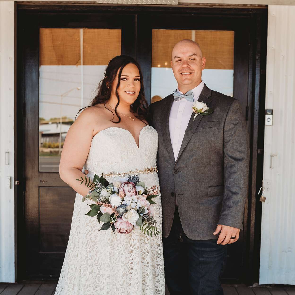 A bride and groom pose for a picture in front of a door