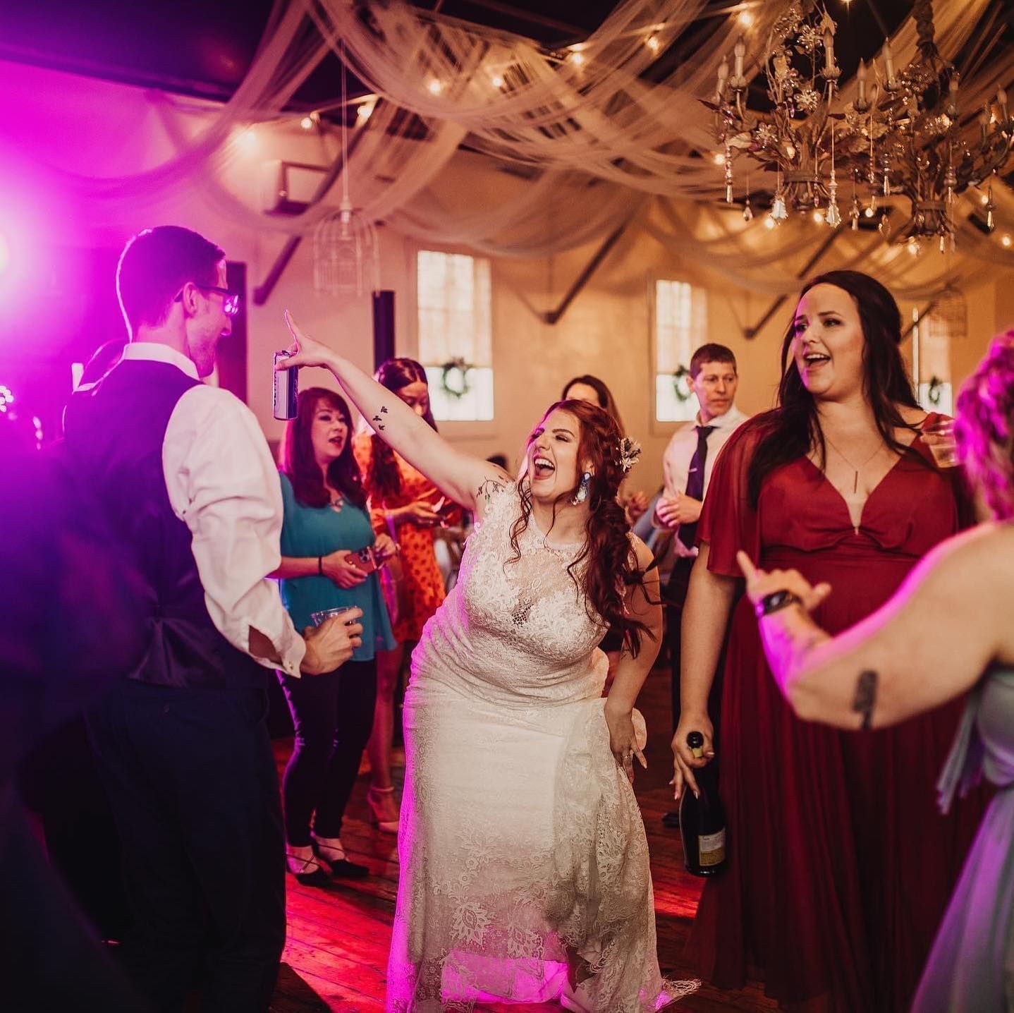 A group of people are dancing in a room with purple lights.