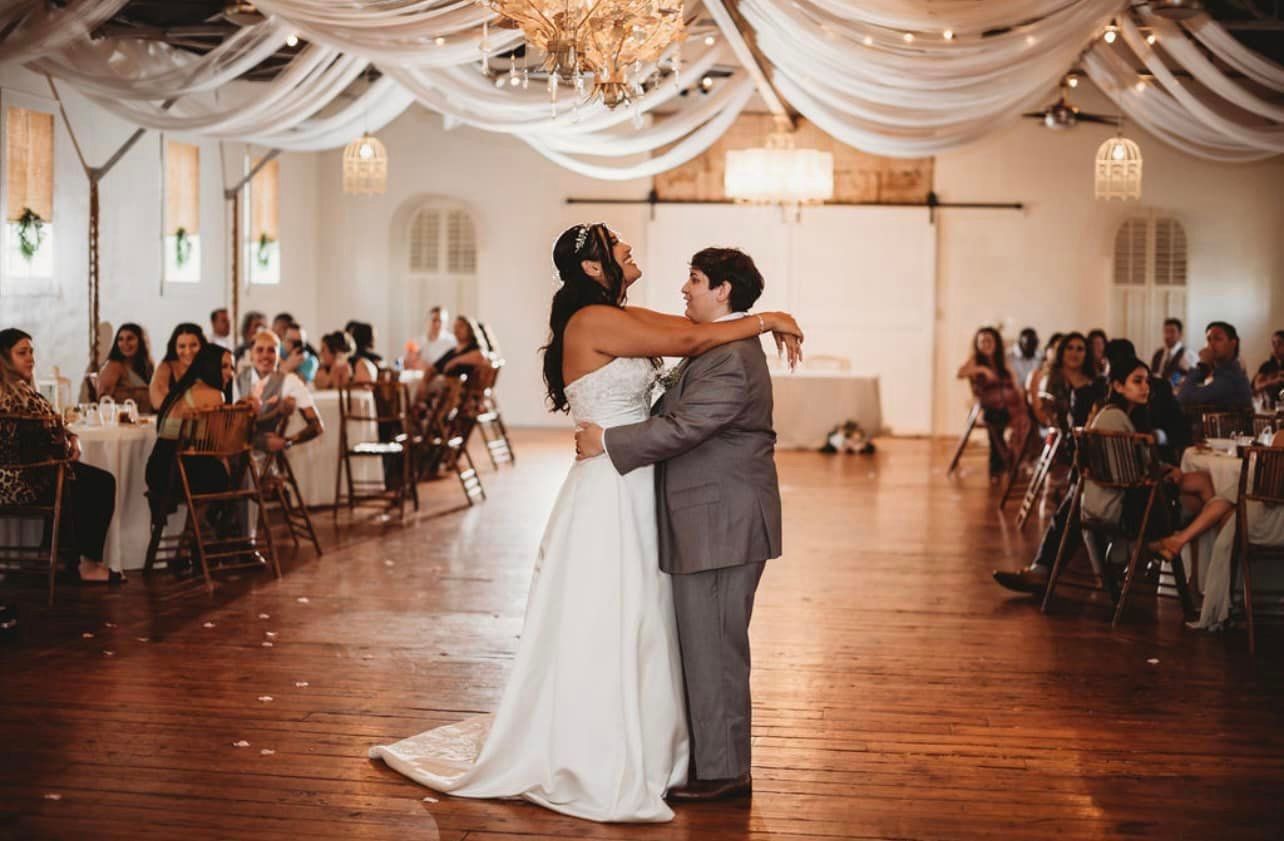 A bride and groom are dancing their first dance at their wedding reception.