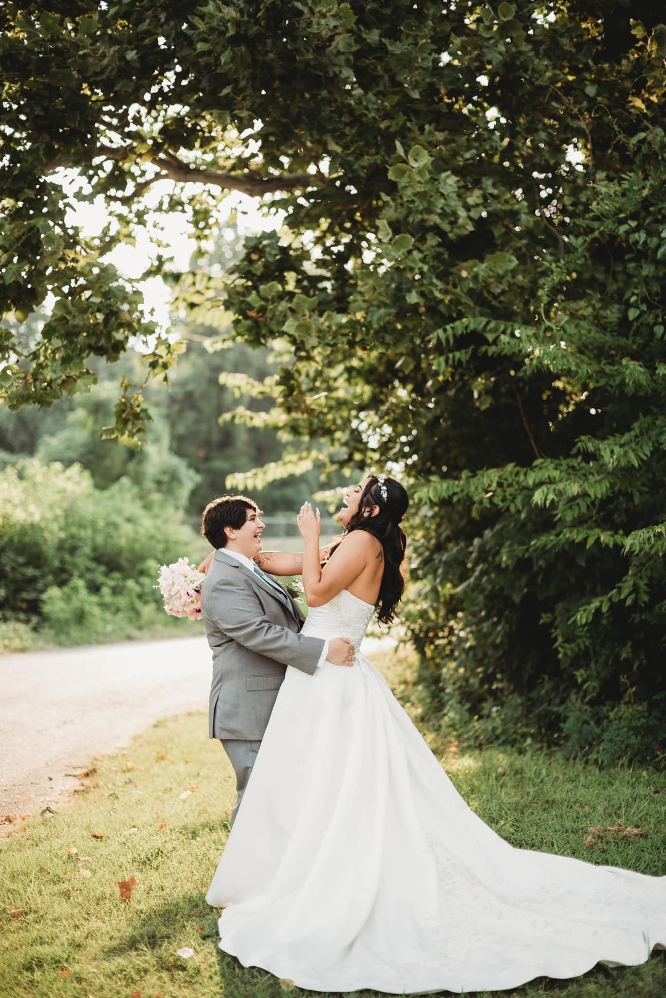 A bride and groom are posing for a picture under a tree.
