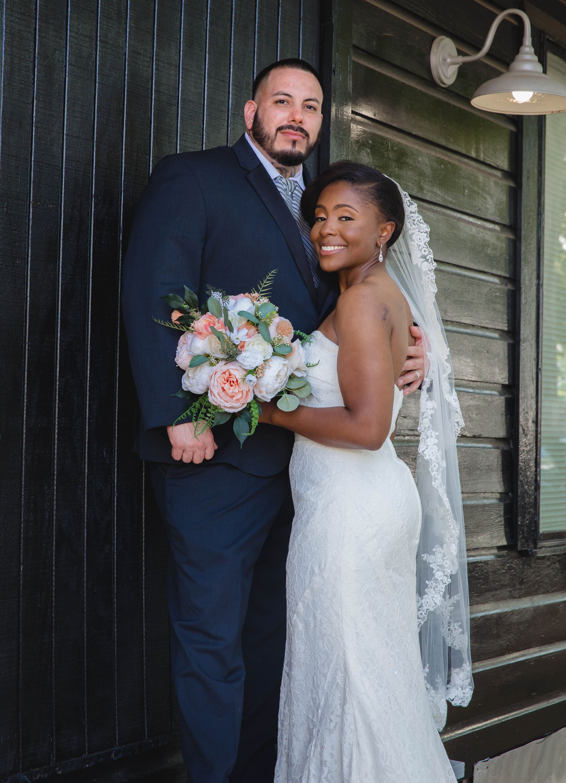 A bride and groom are posing for a picture in front of a building.