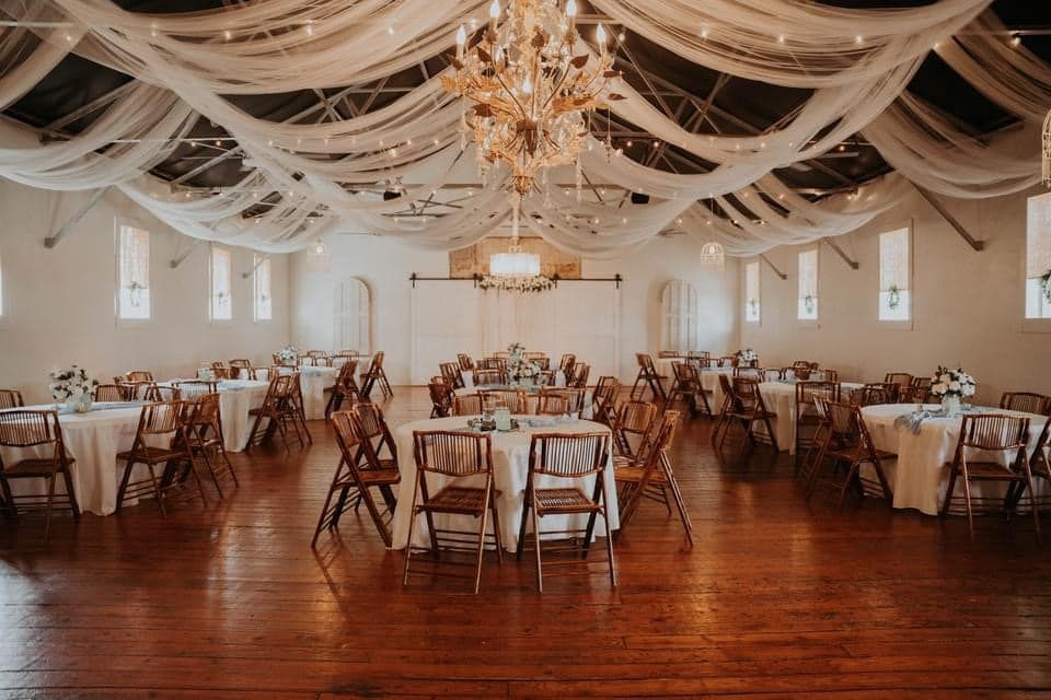 A large room with tables and chairs set up for a wedding reception.