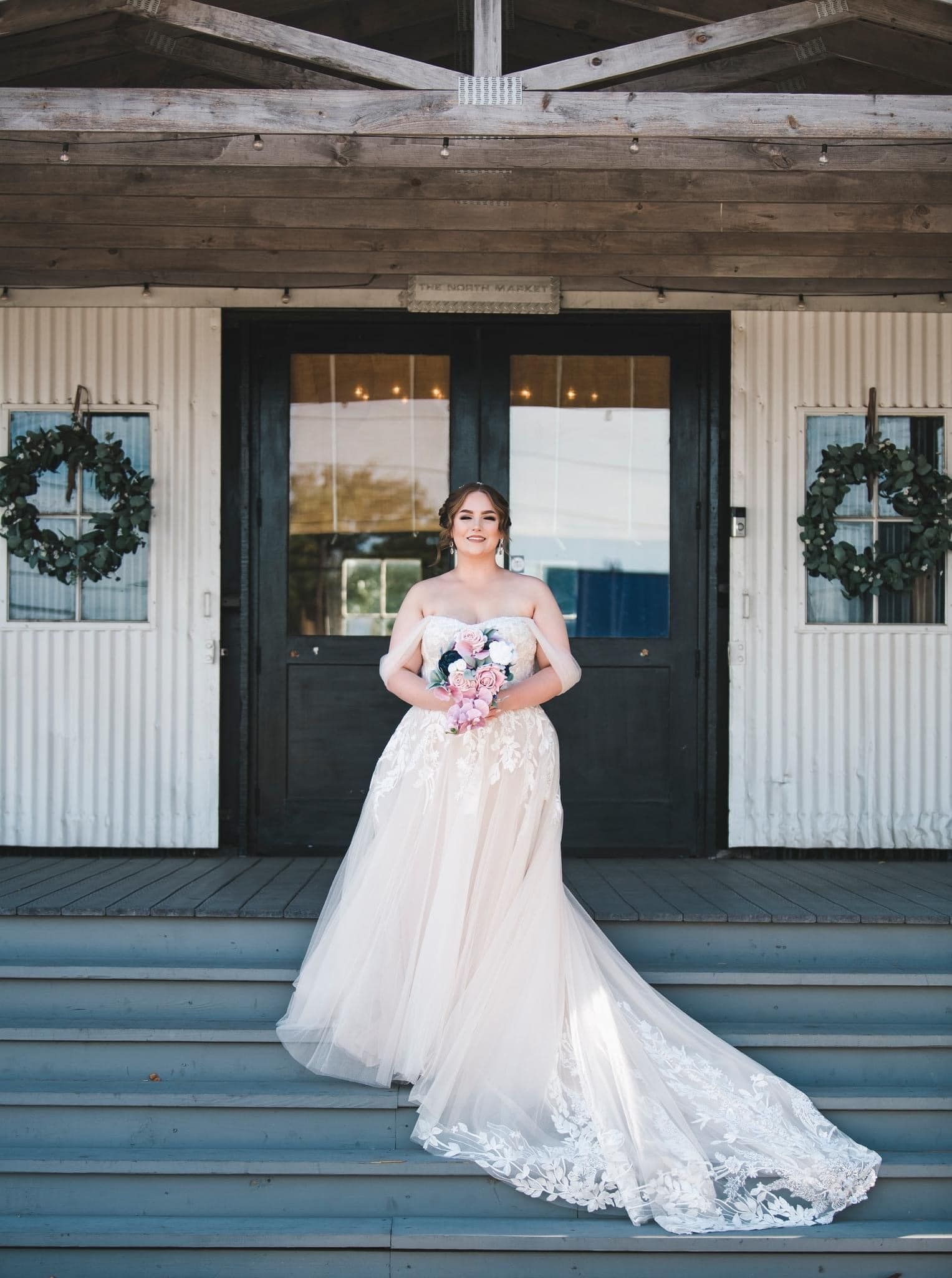 A bride in a wedding dress is standing on the steps of a building.