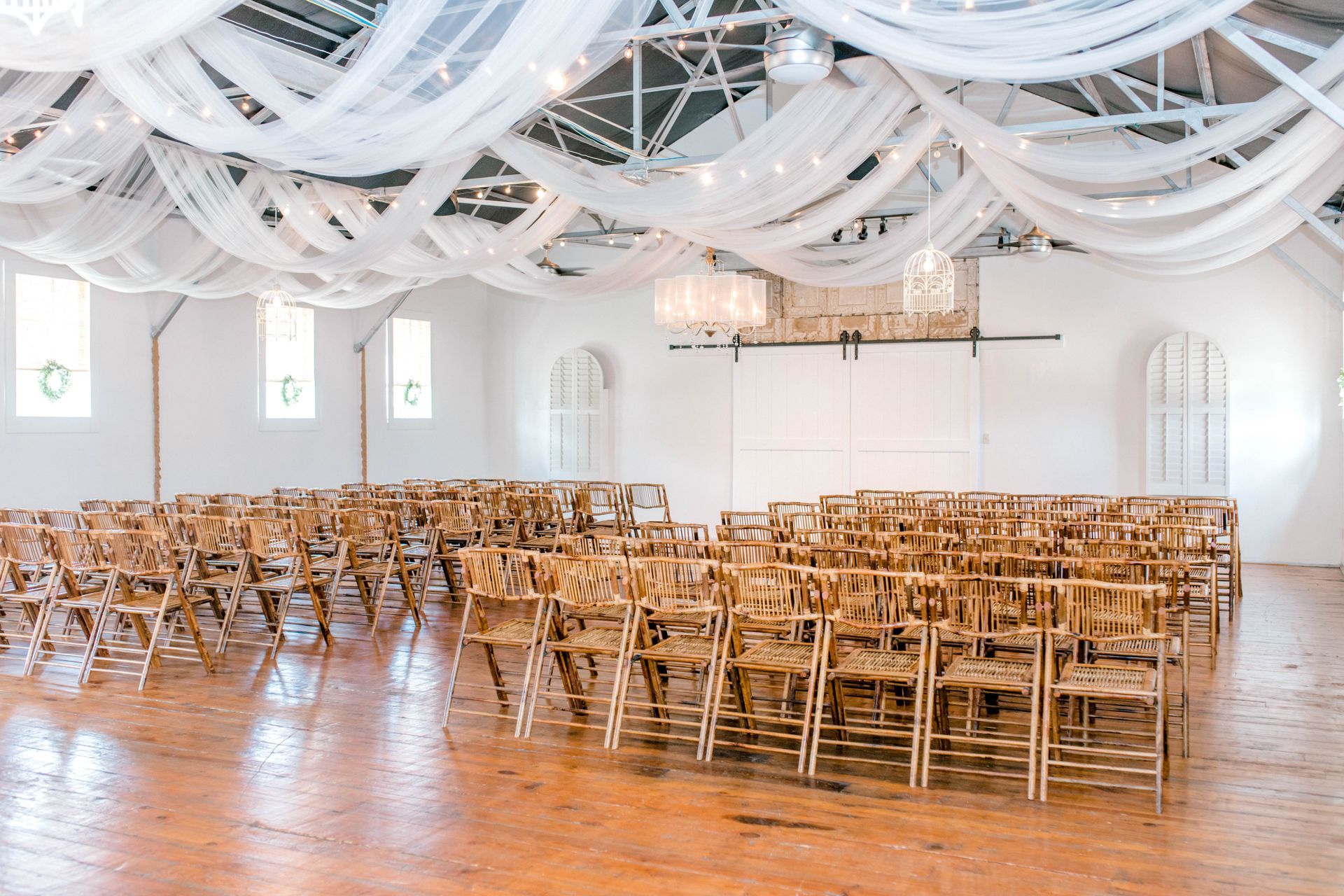 A large room filled with wooden folding chairs and white sheets hanging from the ceiling.