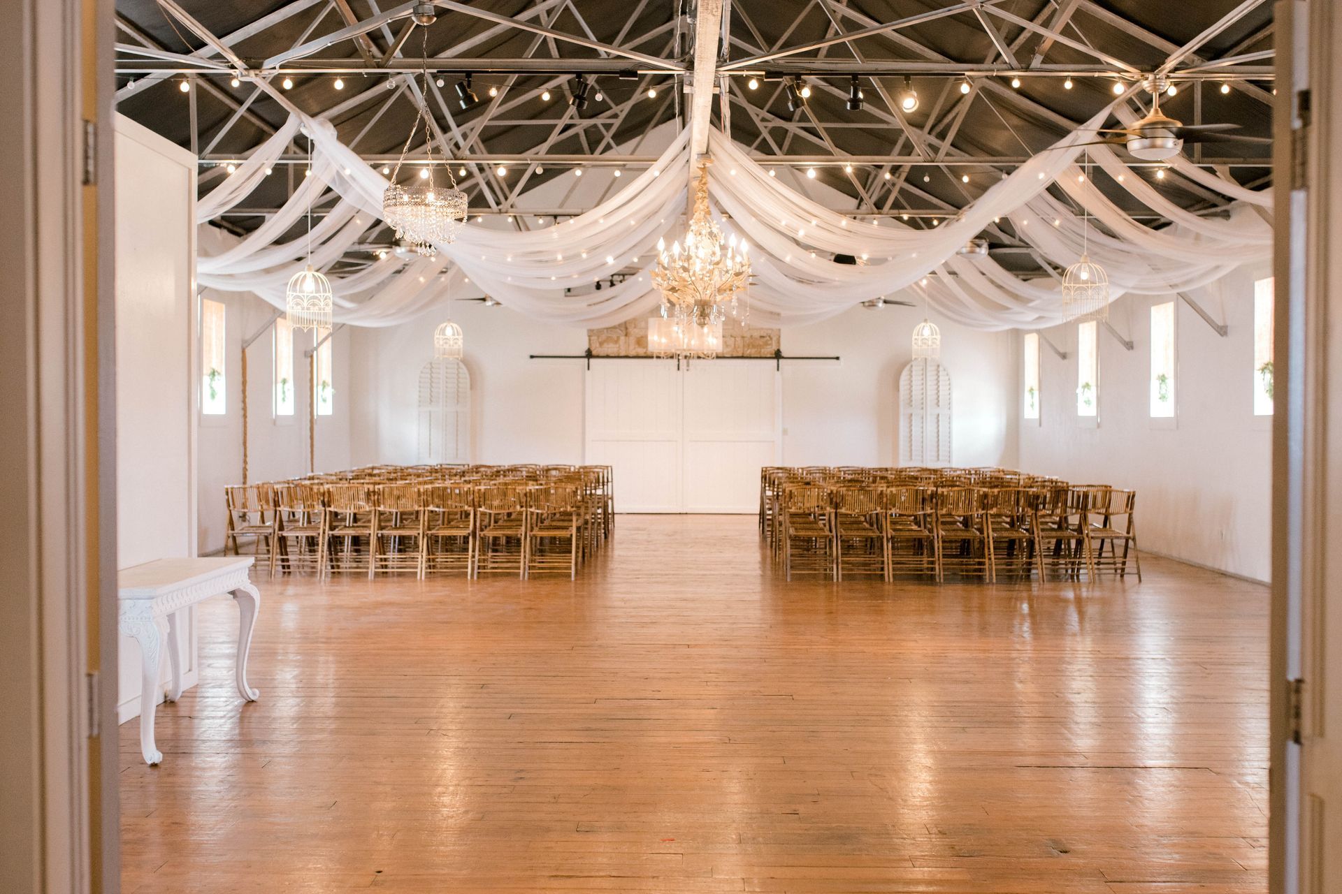 A large empty room with rows of chairs and a chandelier.