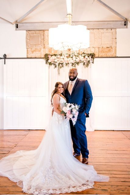 A bride and groom are posing for a picture in a room with a chandelier.