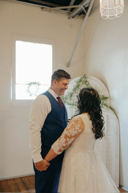 A bride and groom are holding hands and looking at each other in a room.