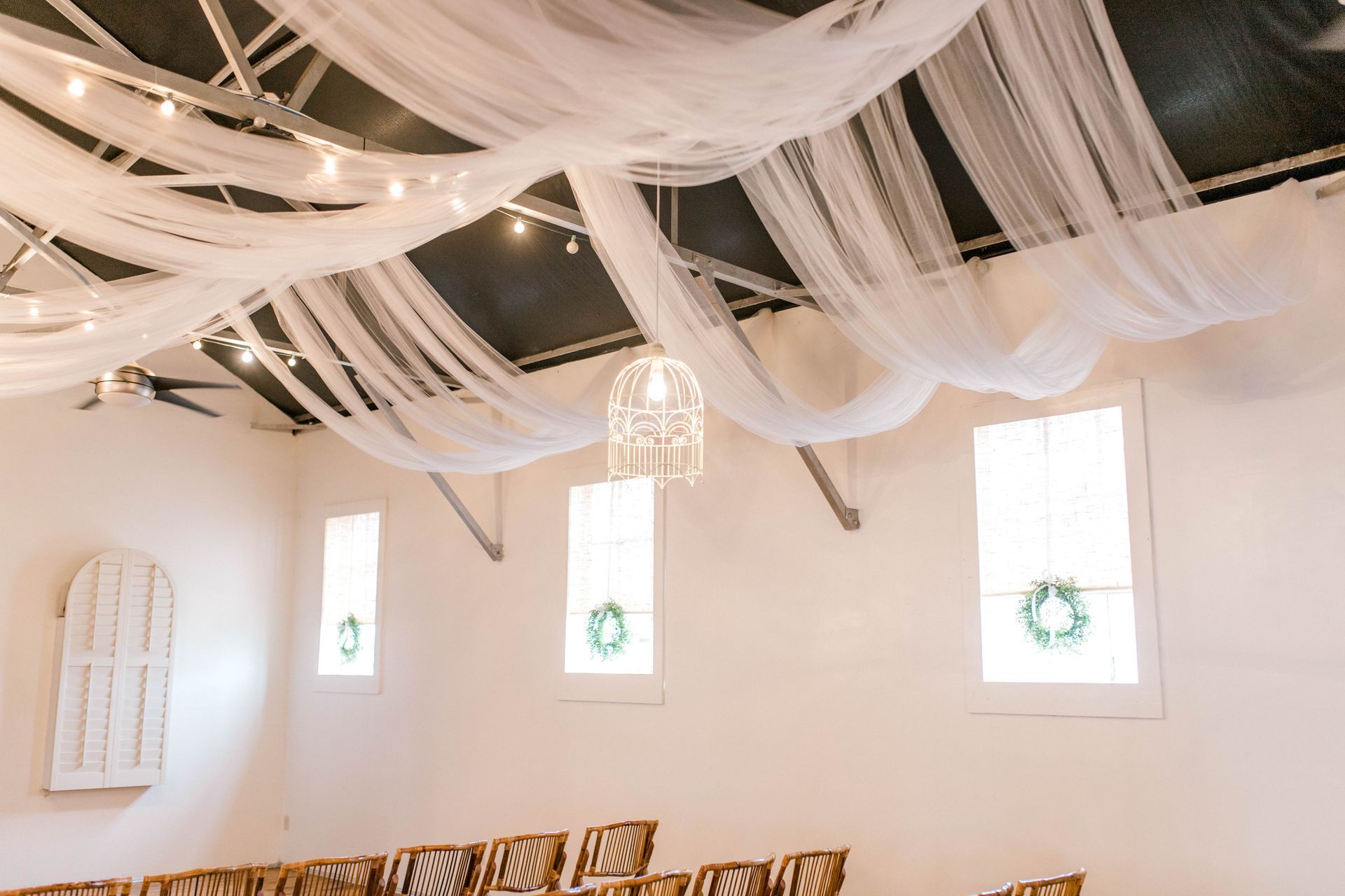 A room with a row of chairs and white curtains hanging from the ceiling.