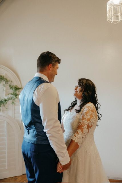 A bride and groom are holding hands and looking at each other in a room.