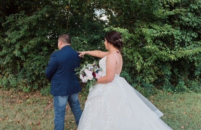 A bride and groom are standing next to each other in a field.