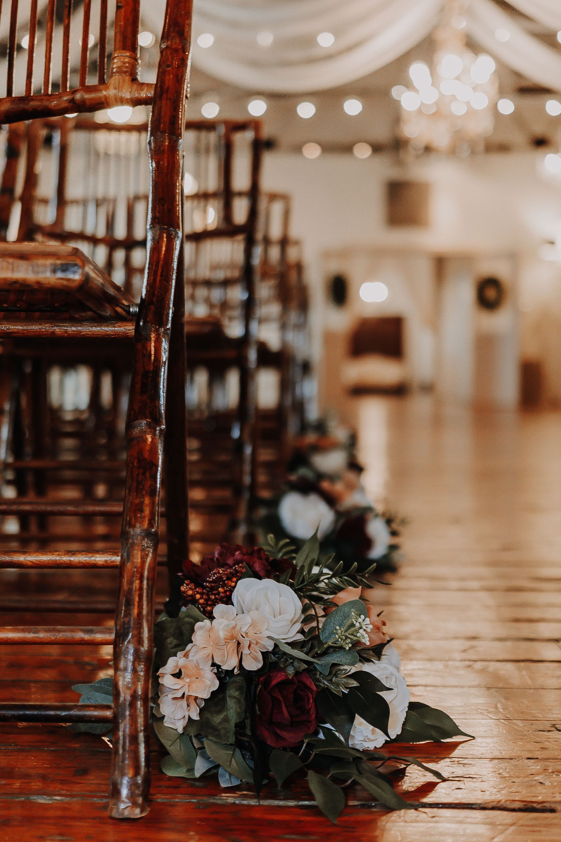 A bunch of flowers are sitting on the floor next to a row of chairs.