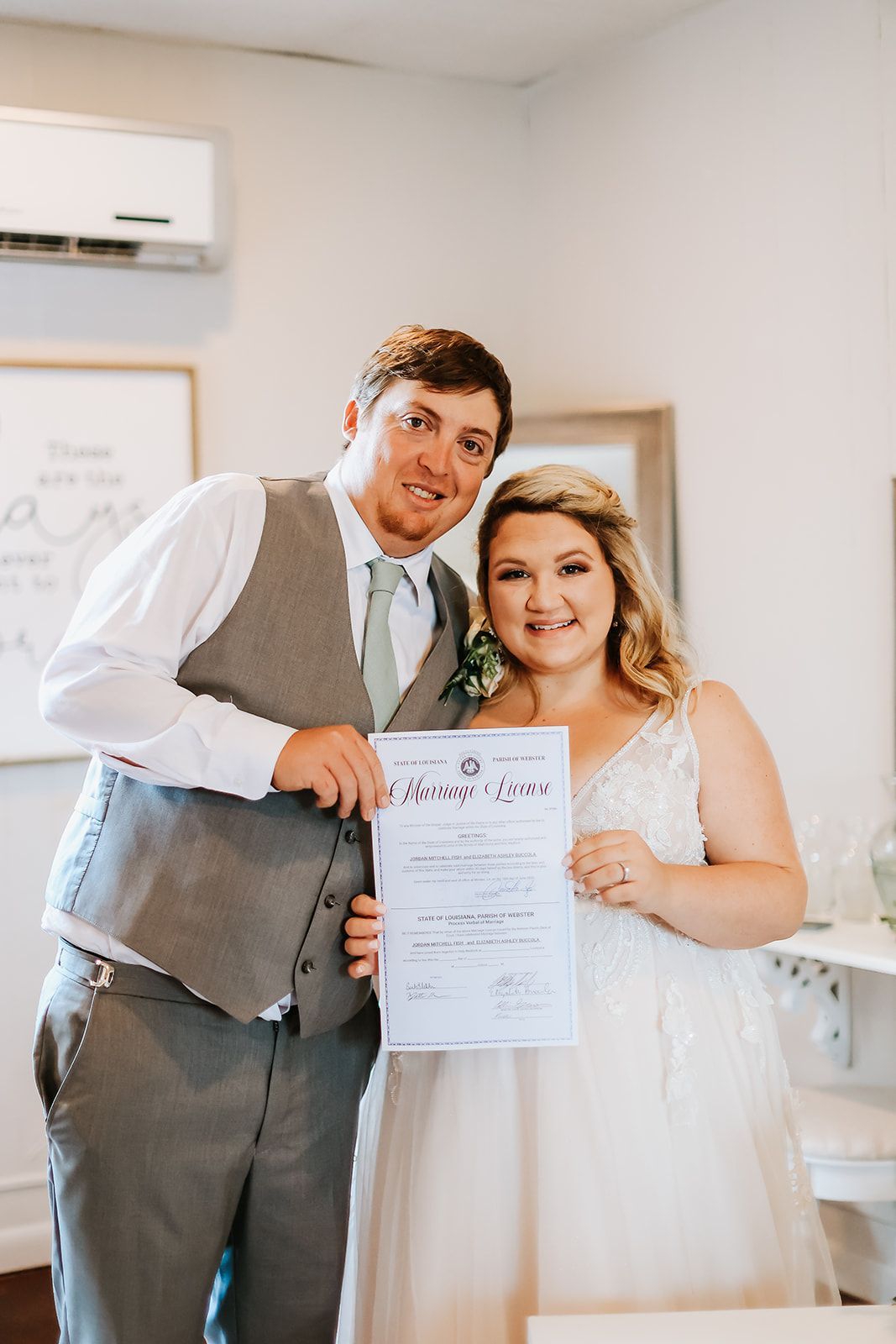 A bride and groom are posing for a picture while holding a wedding certificate.