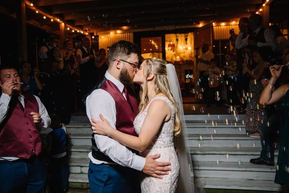 A bride and groom kissing in front of a crowd at their wedding reception.