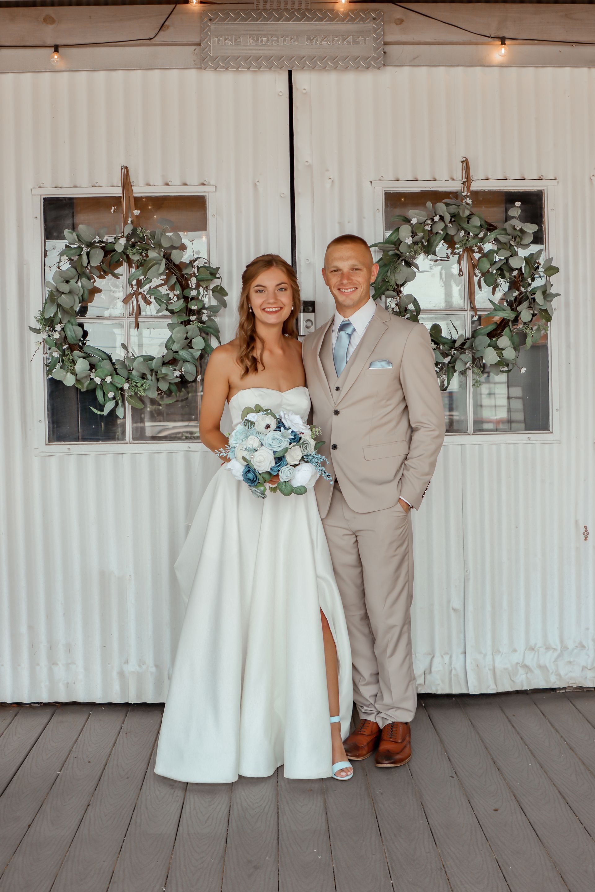 A bride and groom are posing for a picture in front of a white building.