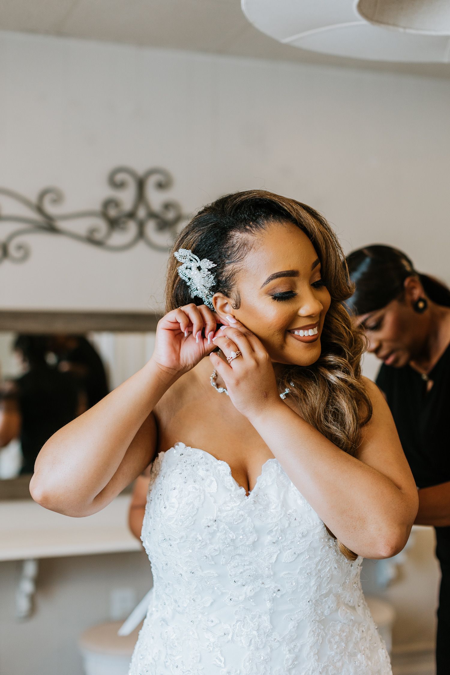 A woman in a wedding dress is putting on her earrings.