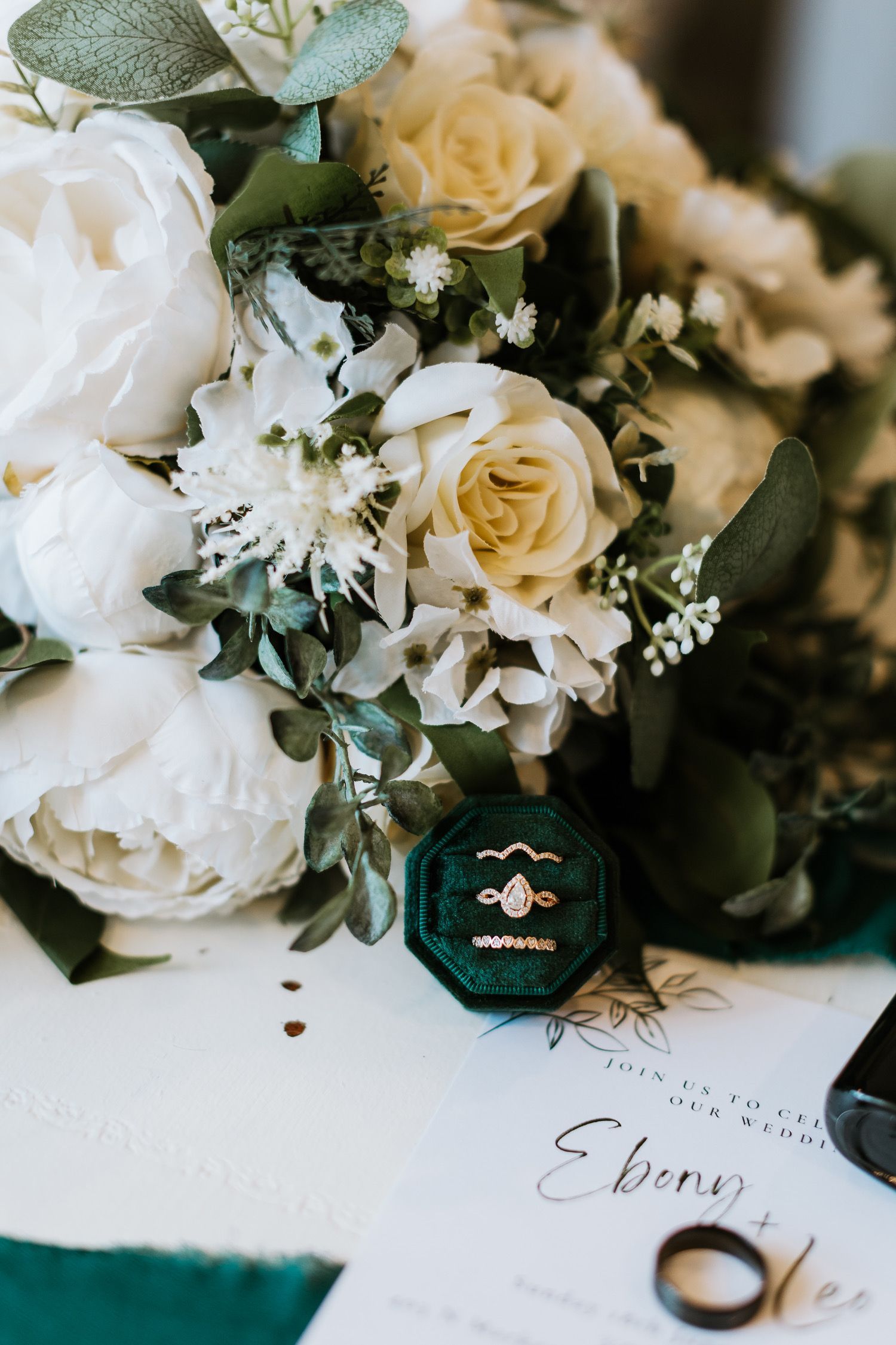 A close up of a bouquet of flowers and wedding rings on a table.