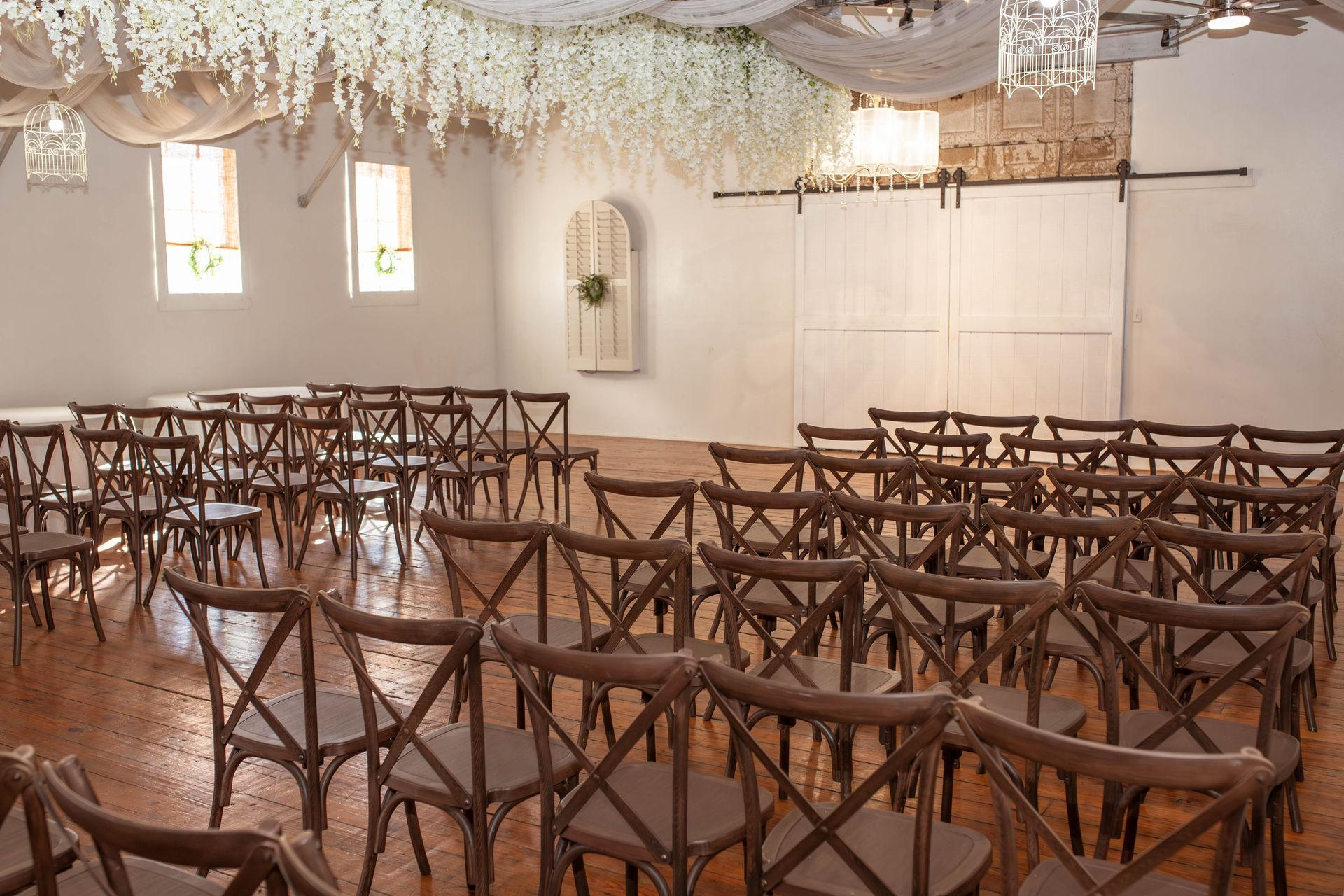 A large room filled with wooden chairs and white sheets hanging from the ceiling.