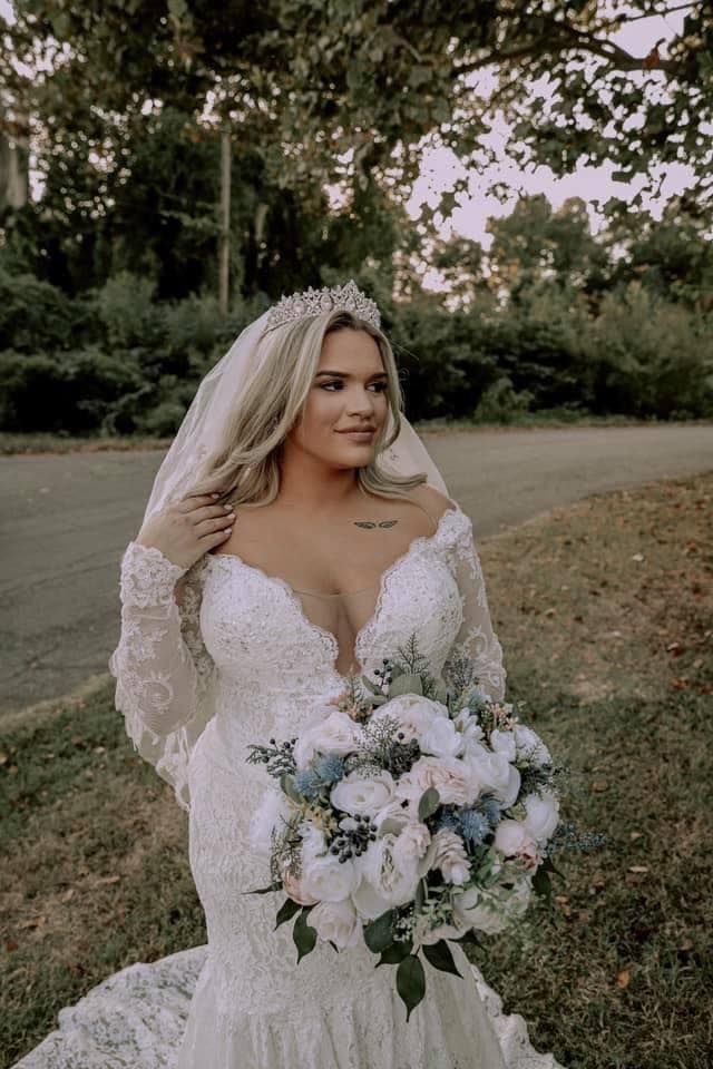 The bride is wearing a veil and holding a bouquet of flowers.