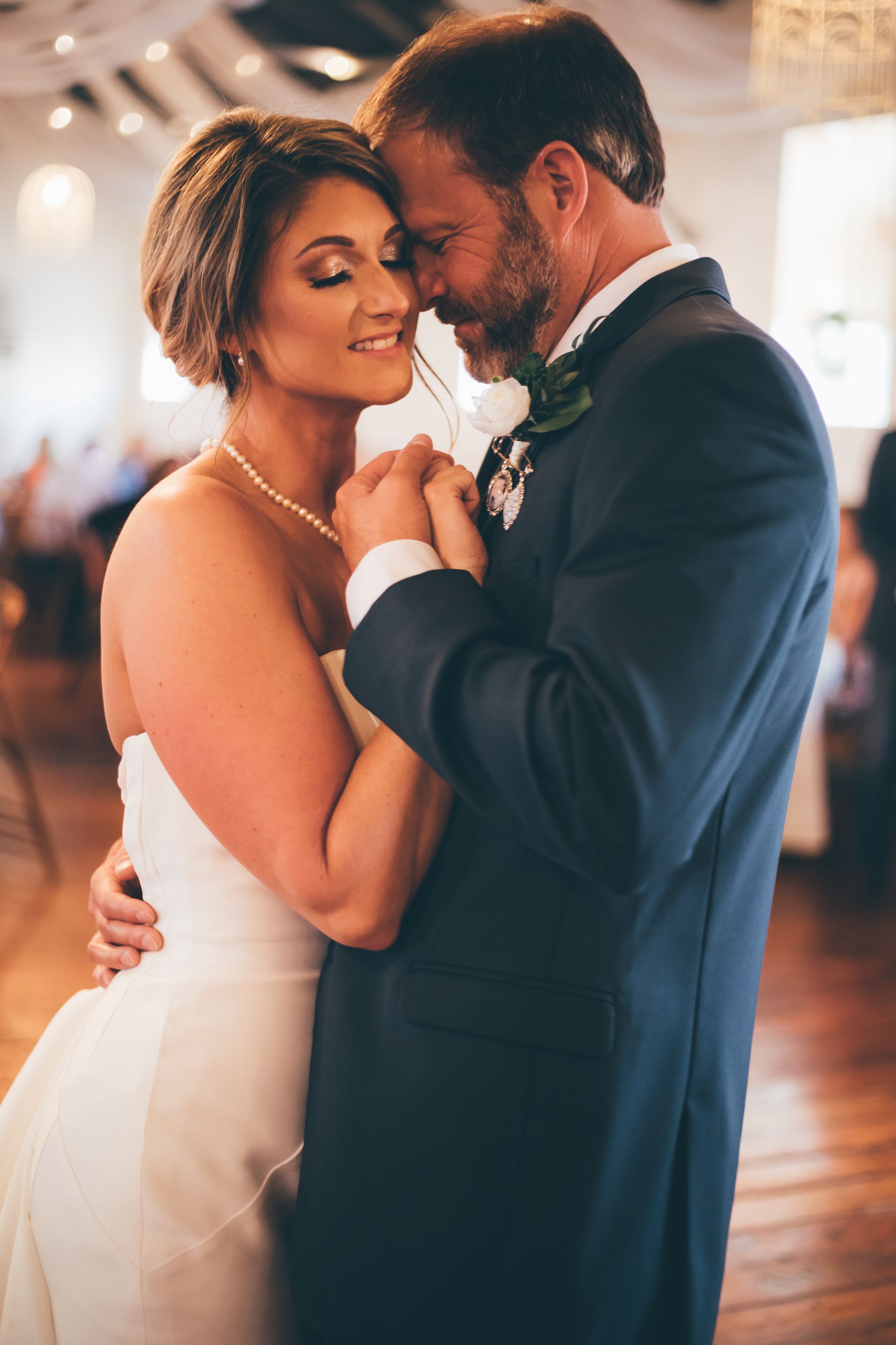 A bride and groom are dancing together at their wedding reception.
