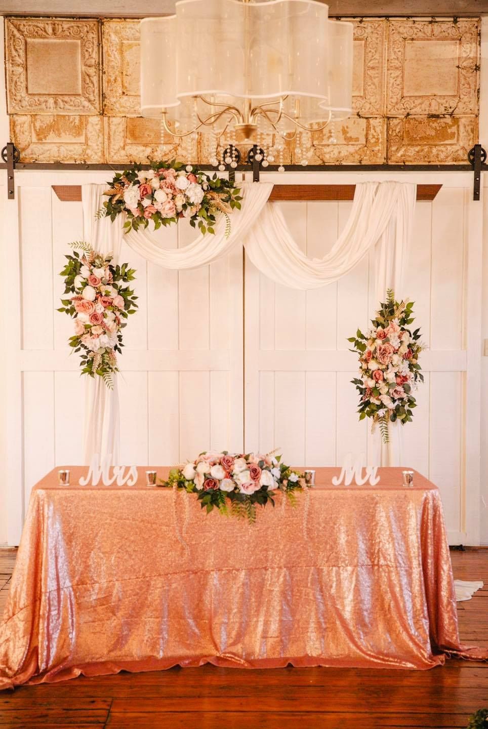 The bride and groom 's table is decorated with flowers and sequins.