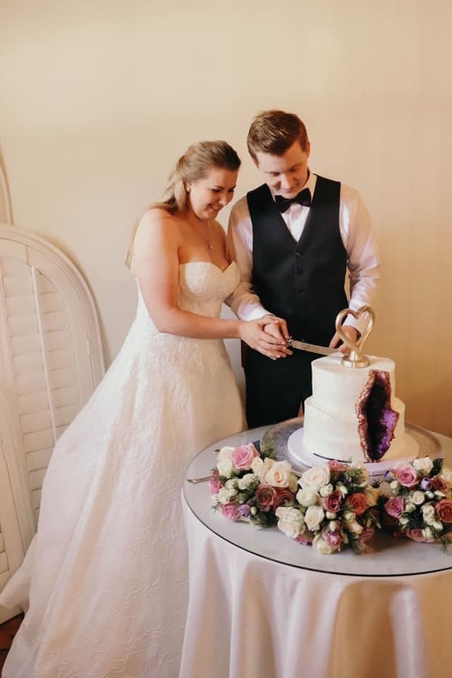A bride and groom are cutting their wedding cake on a table.