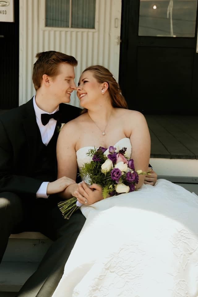 A bride and groom are sitting next to each other on the steps of a building.