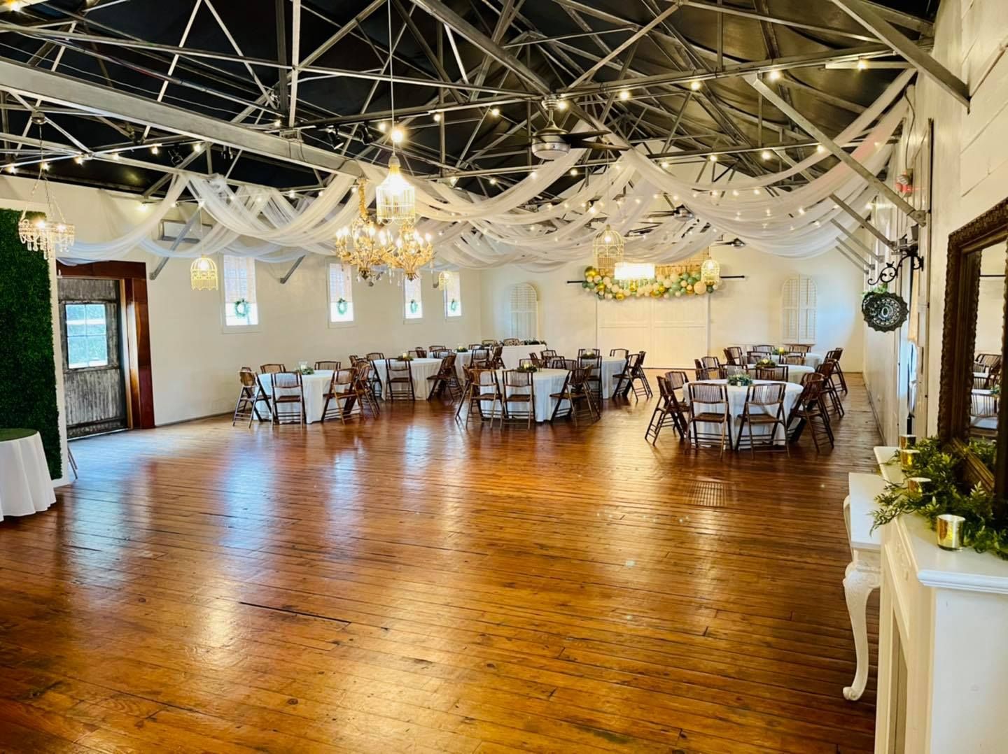 A large room with tables and chairs set up for a wedding reception.