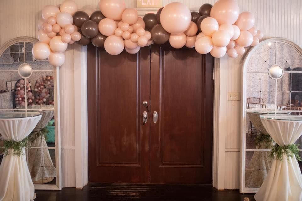 A room decorated with balloons and tables in front of a door.