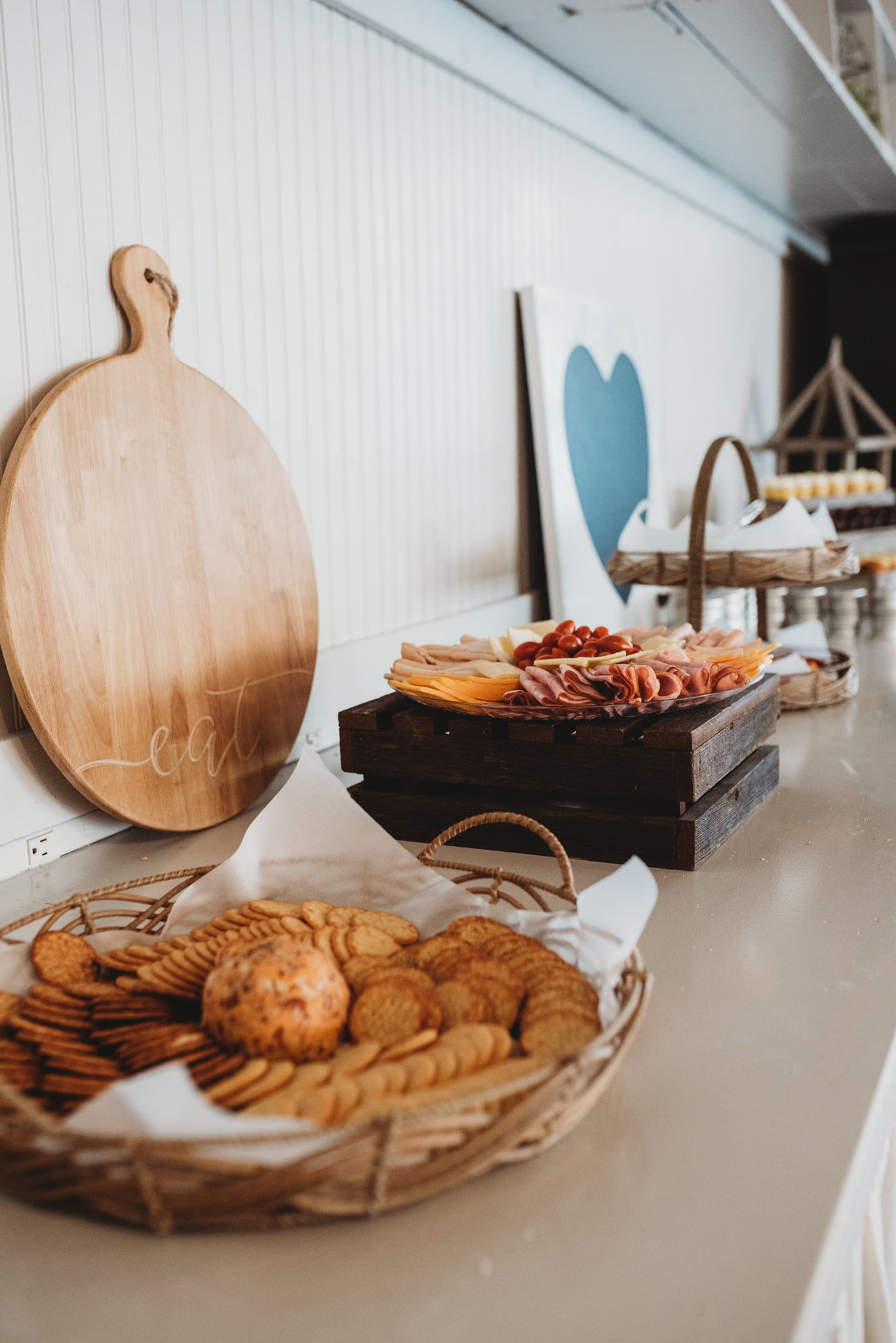 A buffet table with baskets of food and a wooden cutting board.