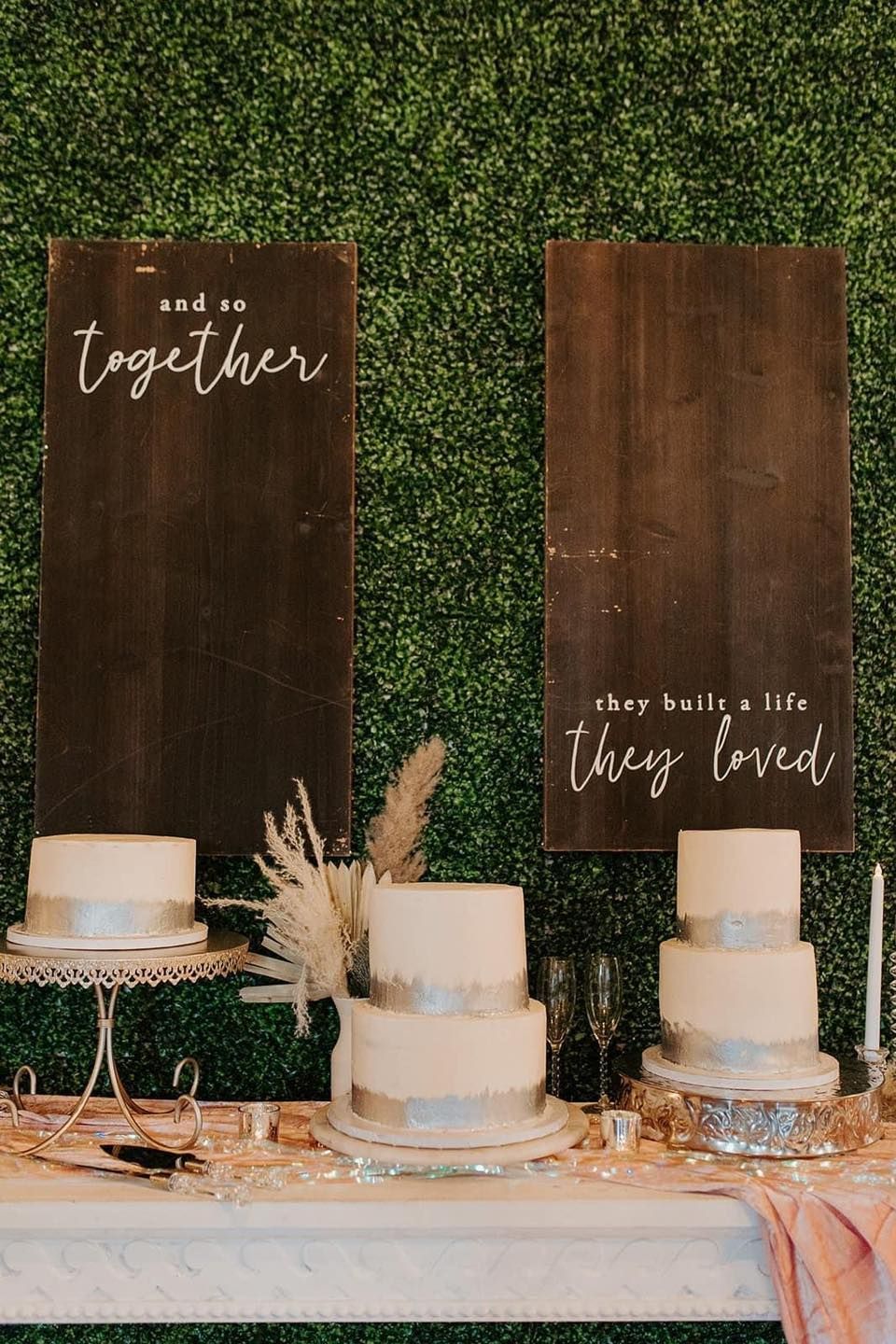 A table with two cakes and two signs on it.