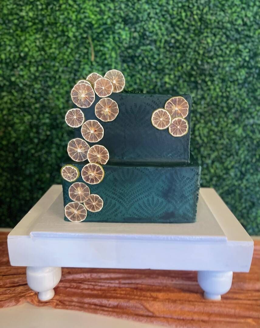 A green cake is sitting on top of a white cake stand.