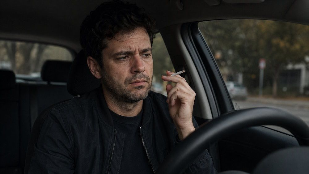 OKC man sitting in his car looking stressed while holding a cigarette