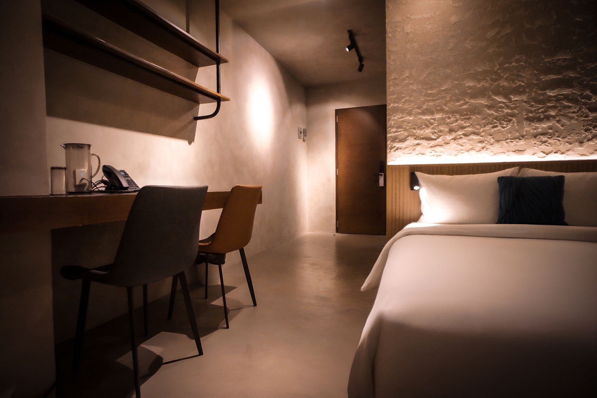 A hotel room with a bed , desk and chairs.