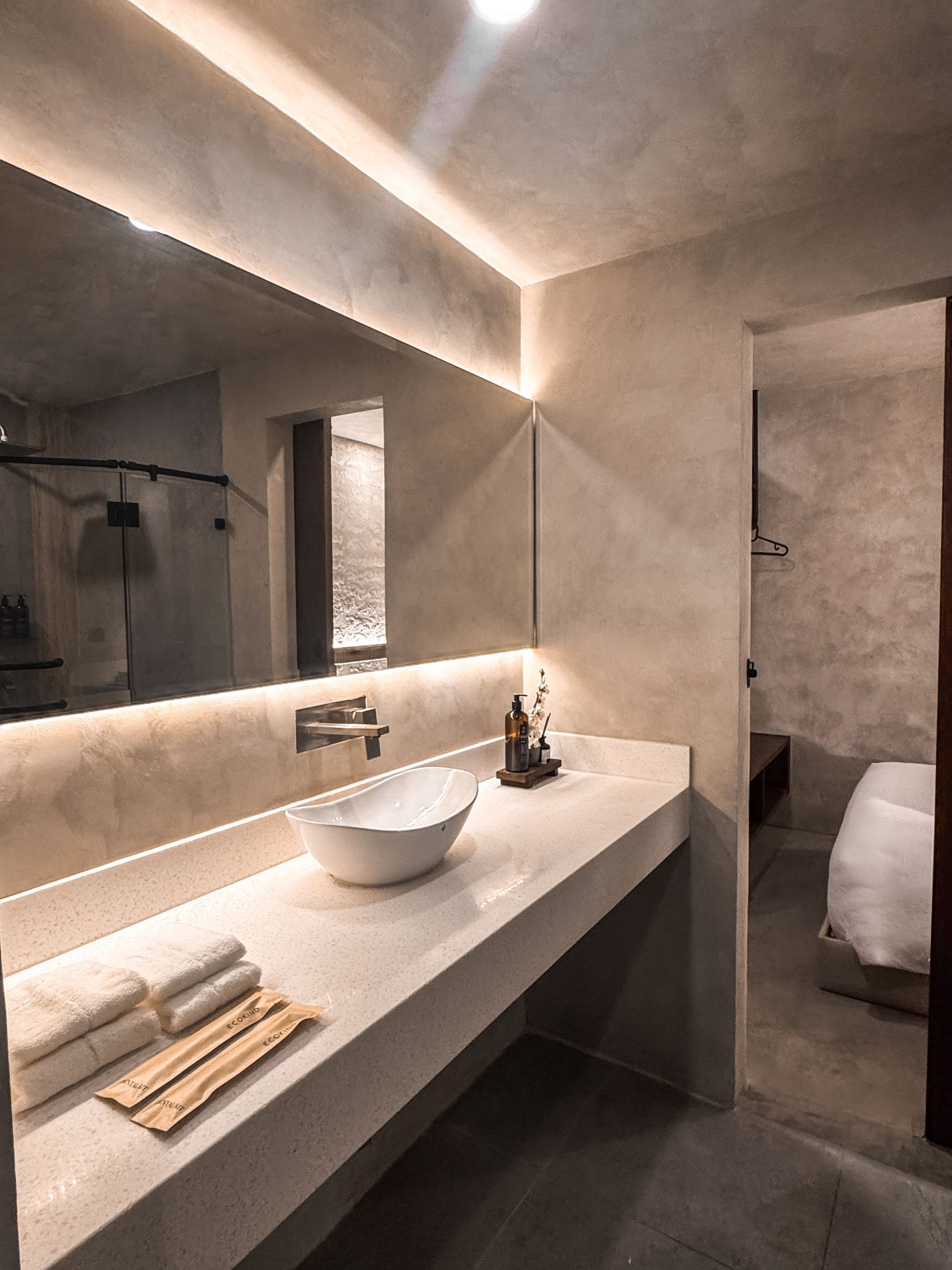 A bathroom with a sink , mirror and towels on the counter.