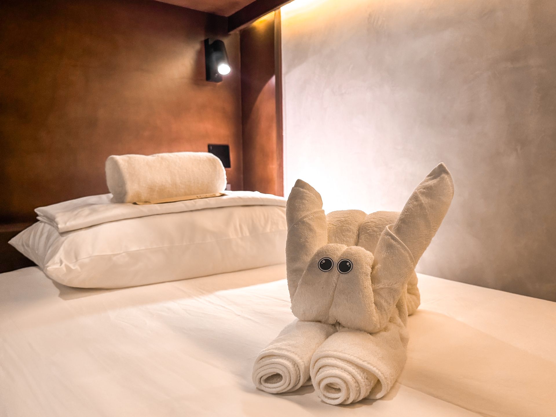 A bed with a towel shaped like a rabbit on it.