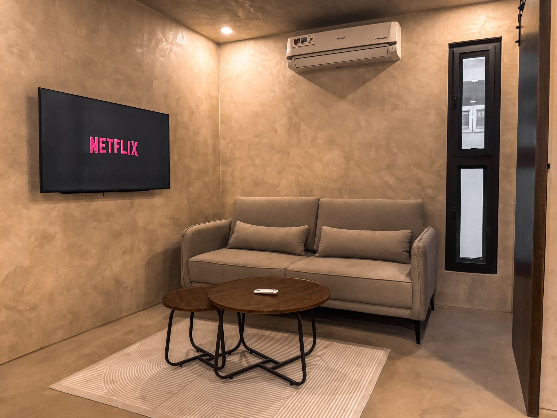 A living room with a couch , table , television and air conditioner.