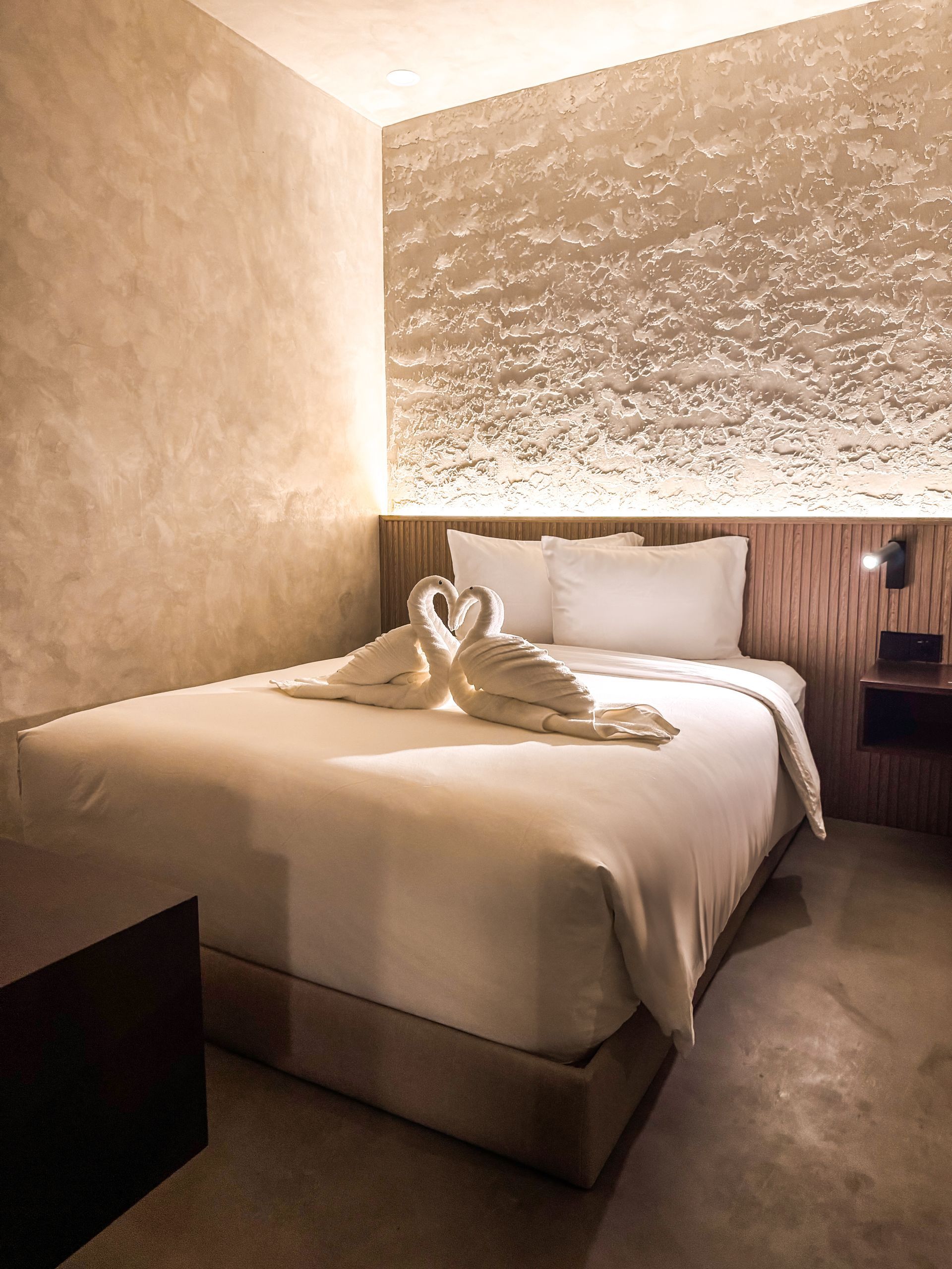 A hotel room with a bed and two swans on it.