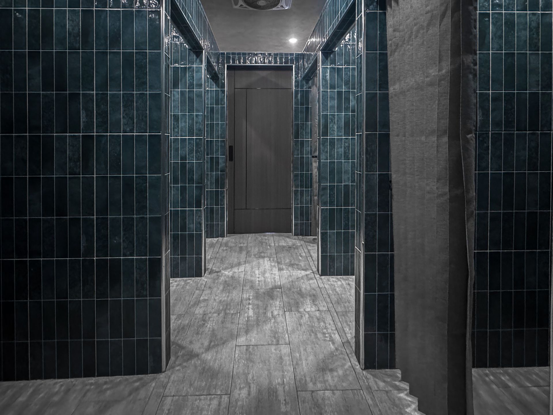 A hallway with blue tiles on the walls and a door.