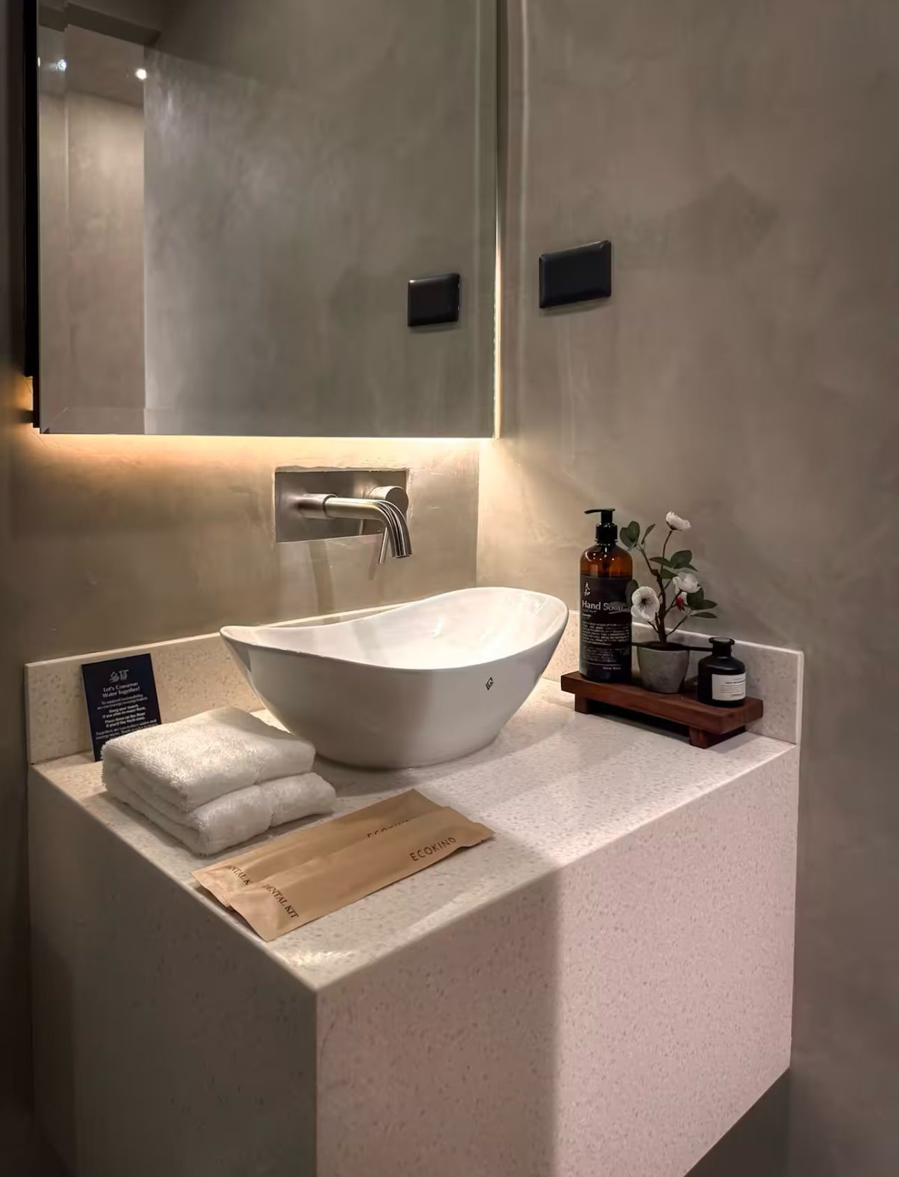 A bathroom with a sink , mirror and towels on the counter.