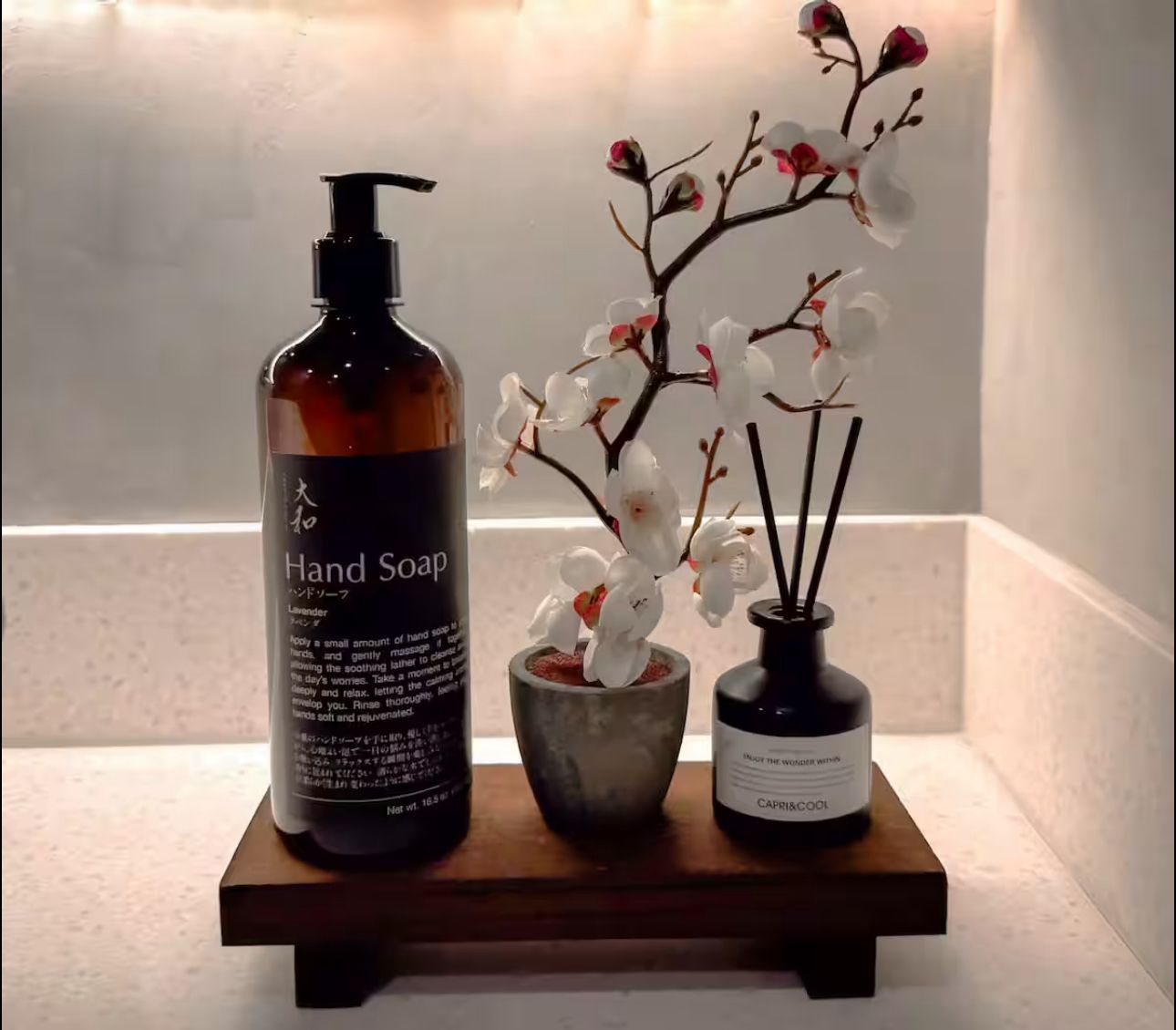 A bottle of hand soap sits next to a vase of flowers