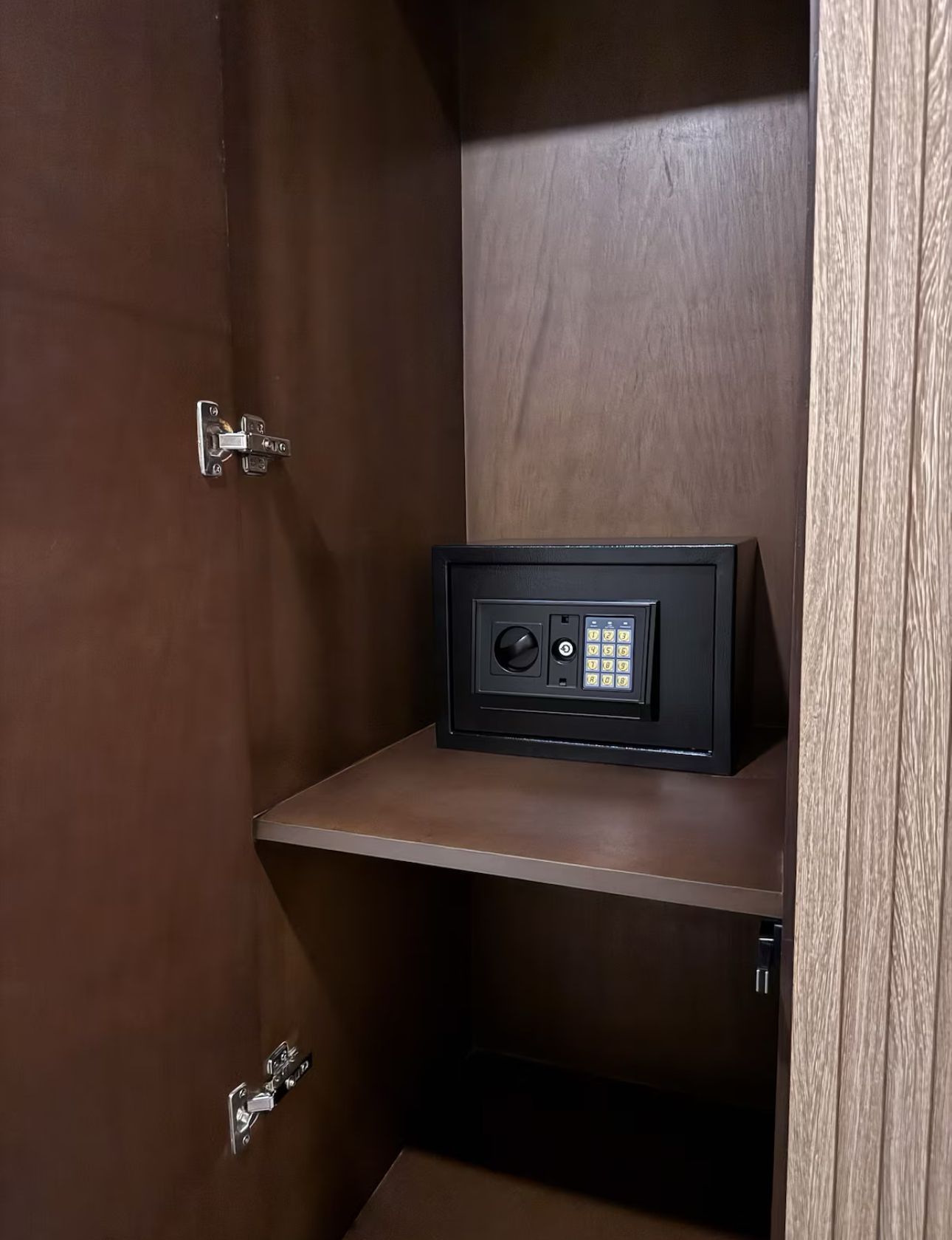 A safe is sitting on a shelf inside of a wooden cabinet.
