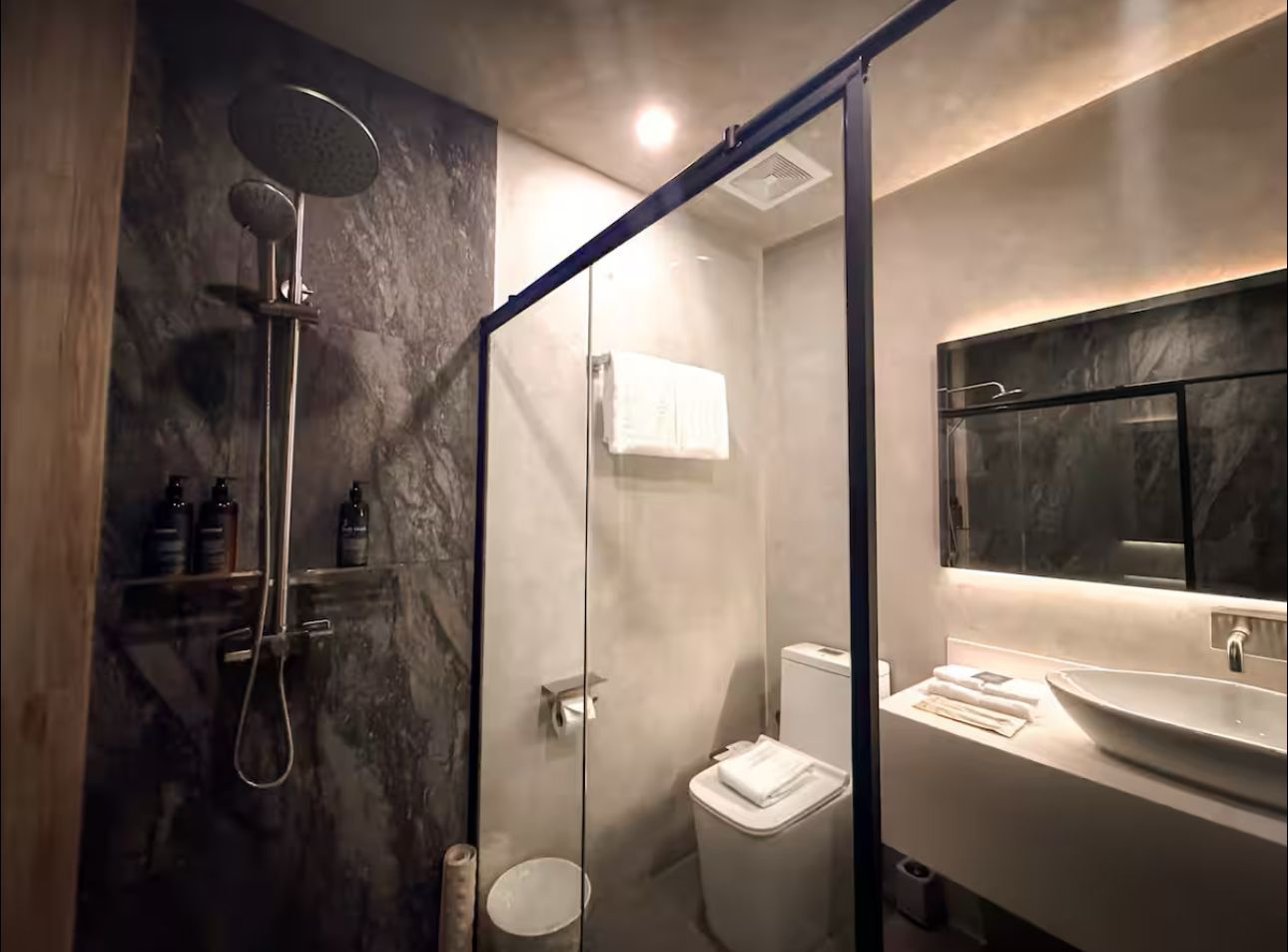 A bathroom with a toilet , sink , shower and mirror.