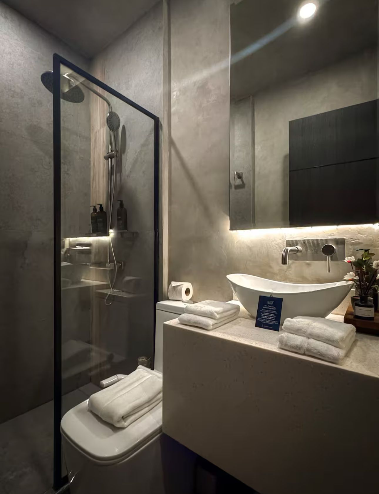 A bathroom with a toilet , sink , mirror and shower.