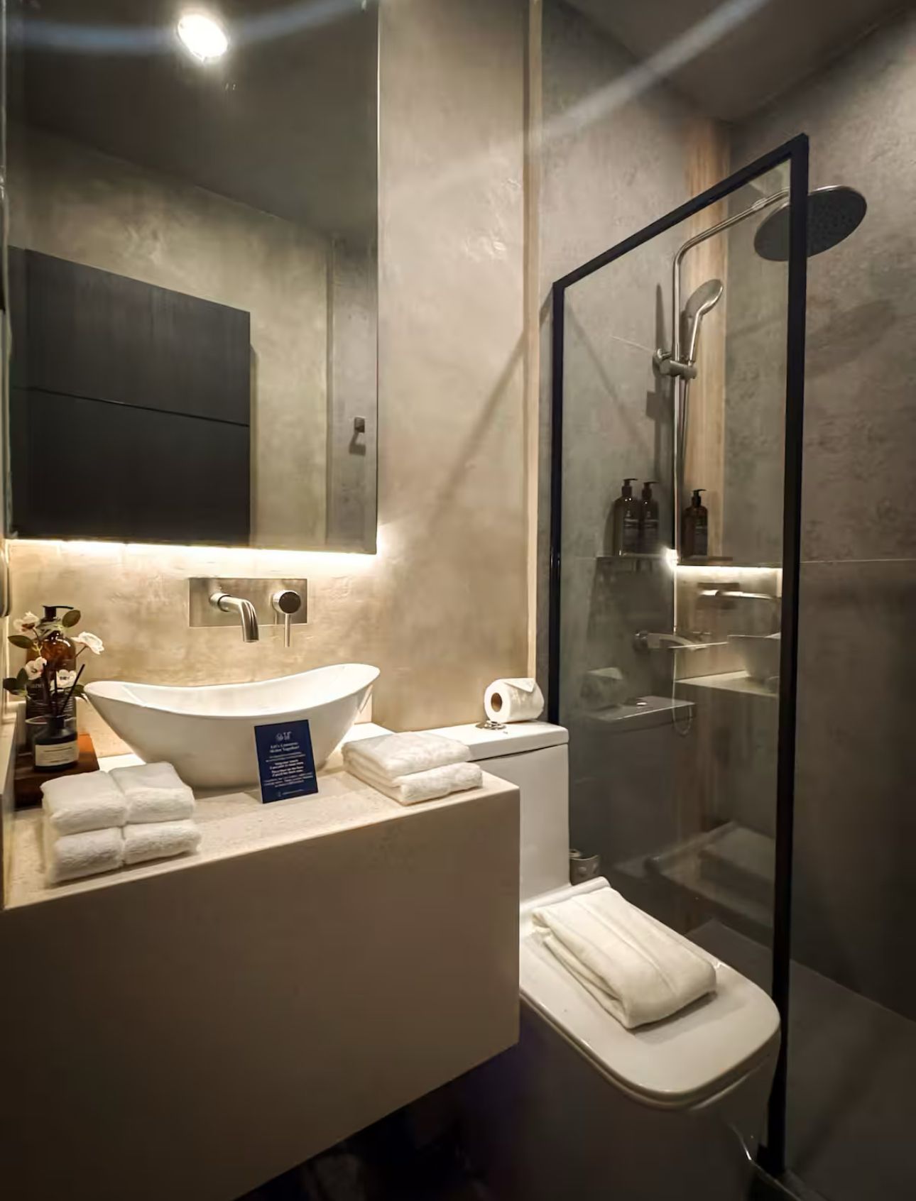A bathroom with a toilet , sink , mirror and shower.